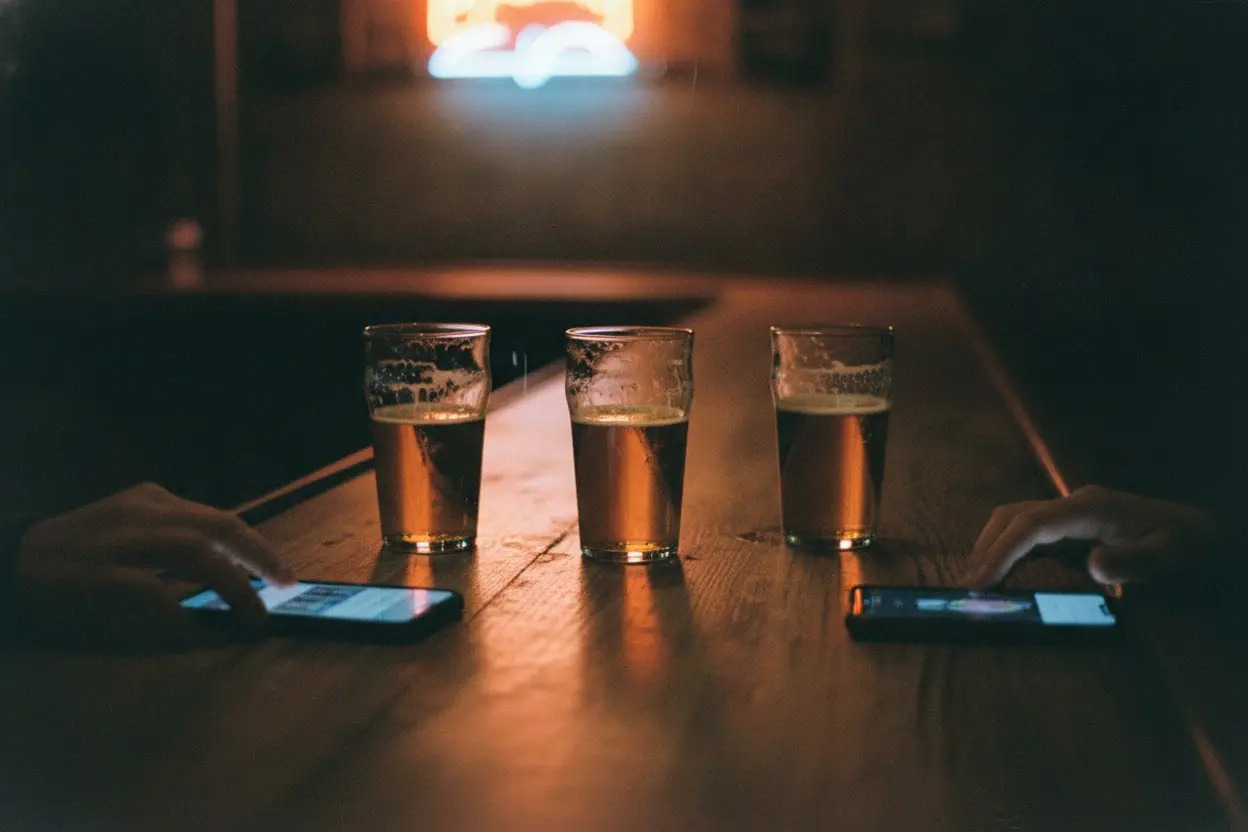 dim bar counter with pint glasses and phones